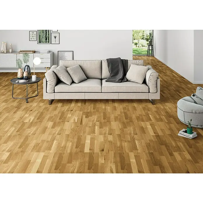 Parquet large roble natural - 1.080 x 198 x 14 mm - Espacio habitable luminoso con un sofá acogedor sobre un suelo de madera cálido y de aspecto natural que da a la habitación un ambiente acogedor.