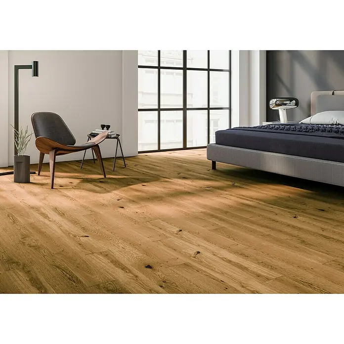 Perfil de transición roble whisky - 2,4 m x 44 mm x 10 mm, Pegado - Elegante interior con suelo de madera, una silla moderna y una cama elegante. El suelo de madera añade calidez y carácter a la habitación.