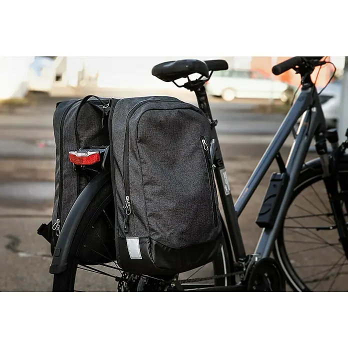 Gepäckträgertasche 2in1 - Volumen: 25 l, Schwarz - Nahaufnahme eines Fahrrads mit zwei grauen Gepäckträgertaschen. Die Taschen sind am Gepäckträger befestigt und haben Reißverschlüsse.
