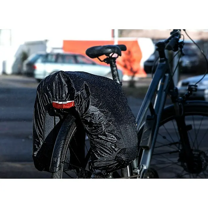 Gepäckträgertasche 2in1 - Volumen: 25 l, Schwarz - Nahaufnahme eines Fahrrads im Regen mit einer wasserdichten Gepäckträgertasche, die das Rücklicht sichtbar lässt.