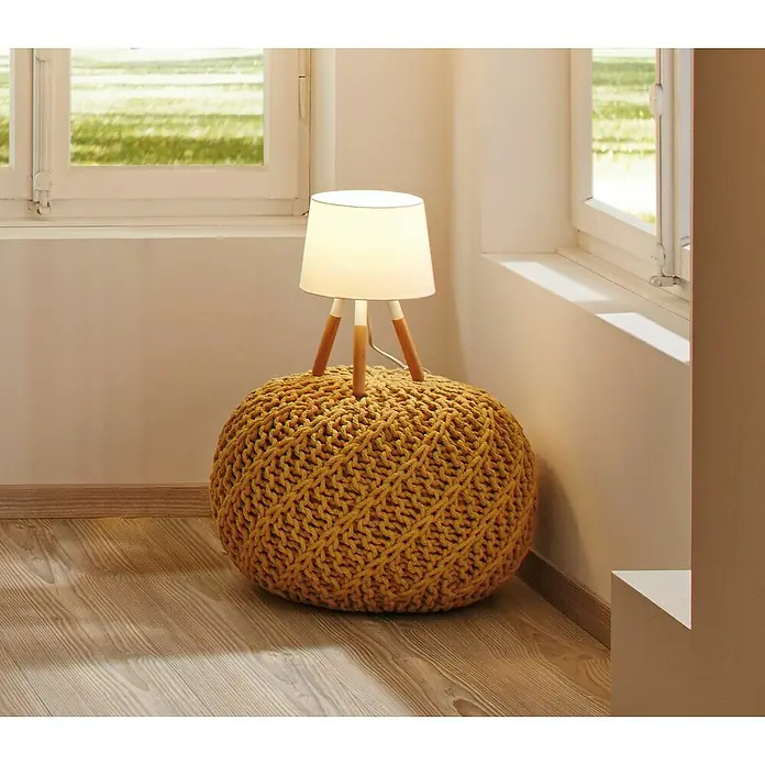 Paulmann Neordic Tischleuchte Berit - 20 W, Hellbraun, E27 - Gemütliches Interieur mit einer gelben Strickpouf, auf der eine Tischlampe mit Holzbeinen steht, vor einem hellen Fenster.