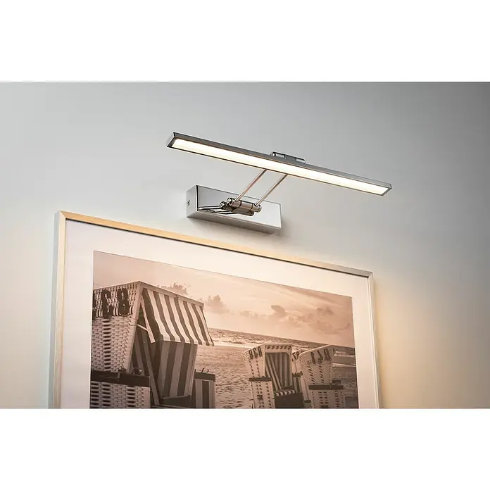Paulmann Galeria LED-Bilderleuchte Beam Fifty - 7 W, L x B x H: 45 x 19 x 4,6 cm, Chrom, Warmweiß - Nahaufnahme einer schwenkbaren, rechteckigen Bilderleuchte aus Chrom über einem gerahmten Schwarzweißfoto mit Strandkorbmotiv.
