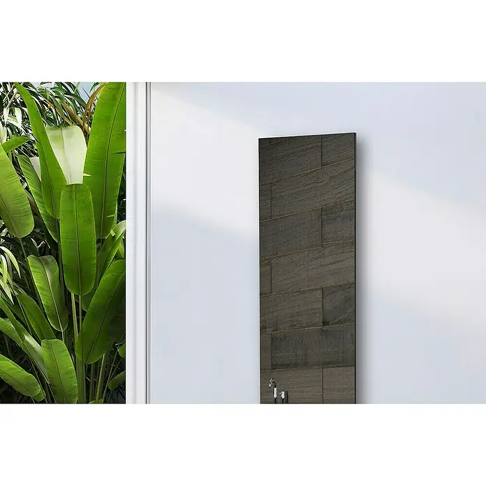 Szagato Designheizkörper Montevideo - B x H: 470 x 1.800 mm, Silber, Ohne Handtuchhalter - Eine moderne, dunkle Heizkörperverkleidung mit Steinmuster an einer weißen Wand, umgeben von üppigem Grün, vereint Funktionalität und stilvolles Design.