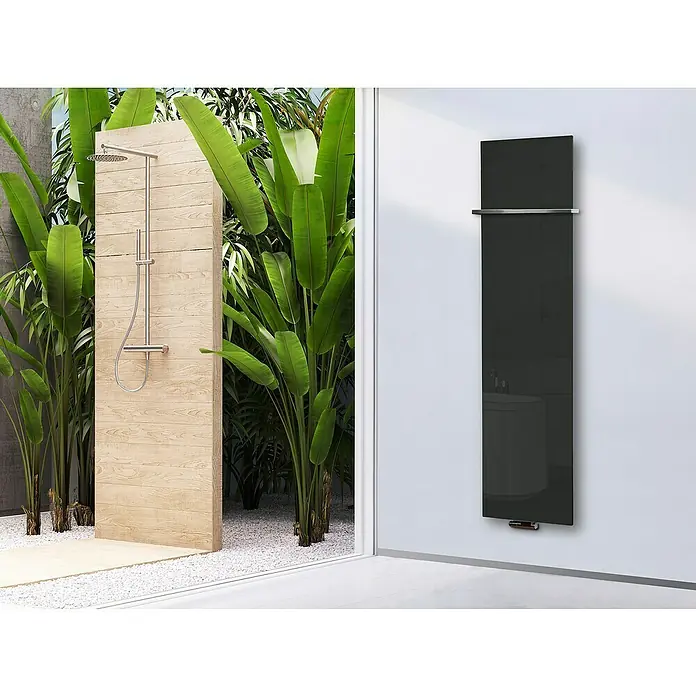 Szagato Designheizkörper Montevideo - B x H: 470 x 1.800 mm, Grau, Silber, Mit 1 Handtuchhalter (15 mm) - Das Bild zeigt einen schwarzen Design-Heizkörper an einer weißen Wand mit einer Dusche und Pflanzen im Hintergrund.