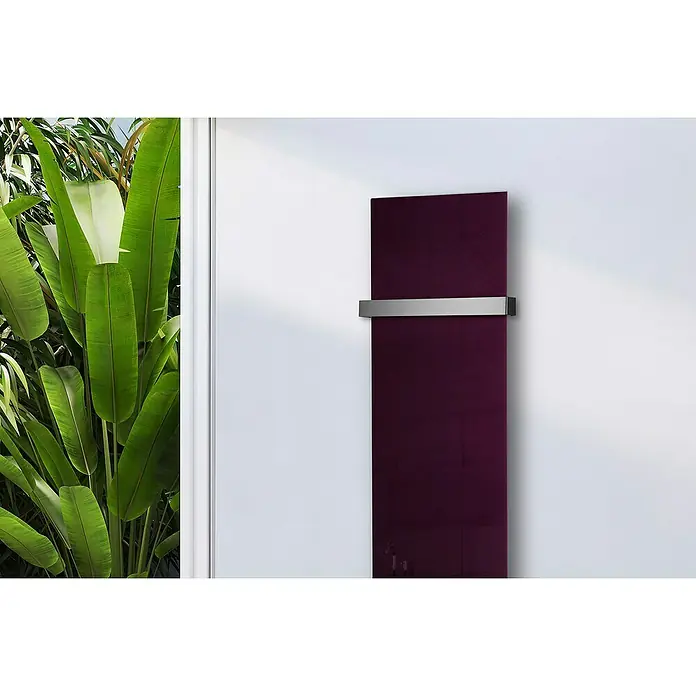 Szagato Designheizkörper Montevideo - B x H: 470 x 1.800 mm, Purpur Violett, Mit 1 Handtuchhalter (50 mm) - Modernes, purpurrotes Handtuchheizgerät mit silberner Halterung an einer weißen Wand, umgeben von tropischen Pflanzen für ein stilvolles Badezimmerambiente.