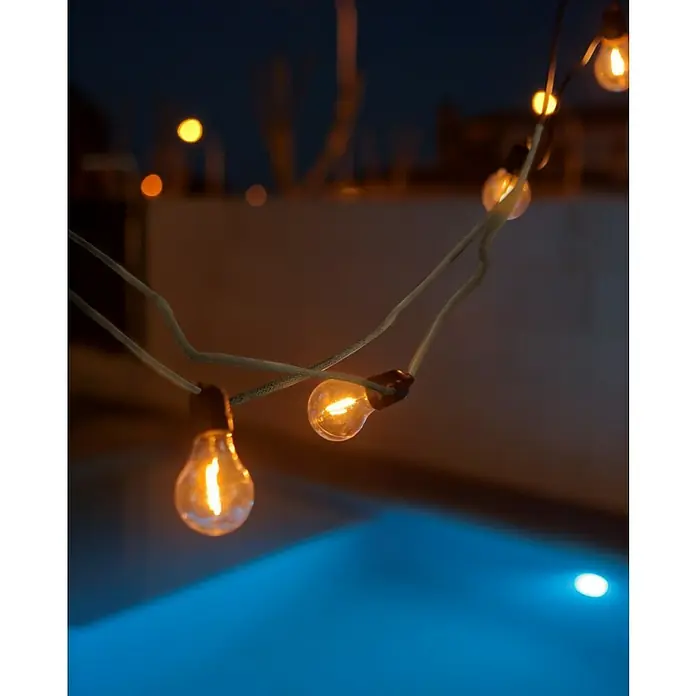 New Garden Guirnalda LED Allegra - 8 m, LED, Color de luz: Blanco cálido, Yute - Una vista iluminadora de una cadena de luces decorativa con bombillas incandescentes de color blanco cálido en el exterior.