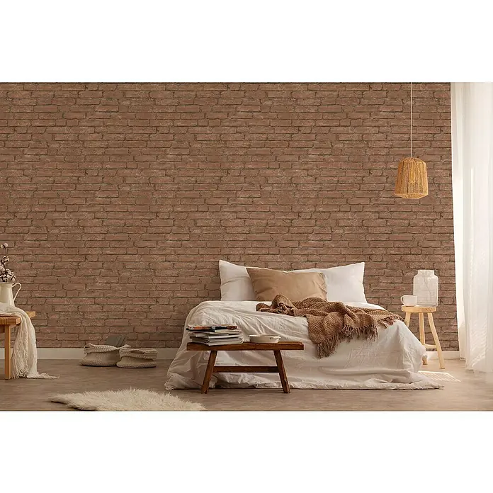 A.S. Création Industrial Vliestapete Ziegelstein - Braun, Steinoptik, 10,05 x 0,53 m - Schlafzimmer mit Backsteinmauer, Bett mit Decke, Nachttisch mit Lampe, Teppich und Beistelltisch mit Büchern.
