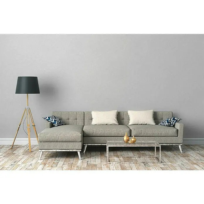 A.S. Création Industrial Vliestapete - Hellgrau, Uni, 10,05 x 0,53 m - Wohnzimmer mit grauem Sofa, Stehlampe und Couchtisch. Das Sofa ist mit hellen Kissen und blauen Akzentkissen dekoriert.