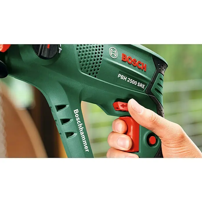 Bosch Bohrhammer PBH 2500 SRE - 600 W, 1,9 J, SDS-Plus-Aufnahme - Nahaufnahme eines Bosch PBH 2500 SRE Bohrhammers in Aktion, der von einer Hand bedient wird. Das grüne Werkzeug mit roten Akzenten ist im Fokus.