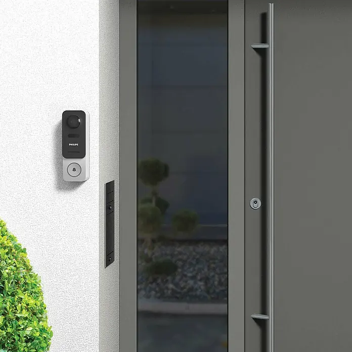 Philips WelcomeEye Farb-Video-Türsprechanlage Link - 1.920 x 1.080 Pixel (Full HD), Schwarz/Grau - Bild einer Philips-Türklingel mit Kamera, montiert an einer weißen Wand neben einer modernen Haustür.