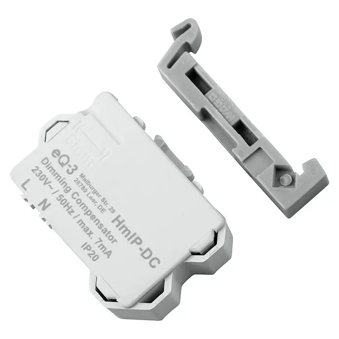 Homematic IP Kompensator HmIP-DC für Dimmer - 16 x 39 x 28 mm - Nahaufnahme eines eQ-3 HmIP-DC Dimmkompensators und einer Halterung, die intelligente Hausbeleuchtungslösungen hervorheben.