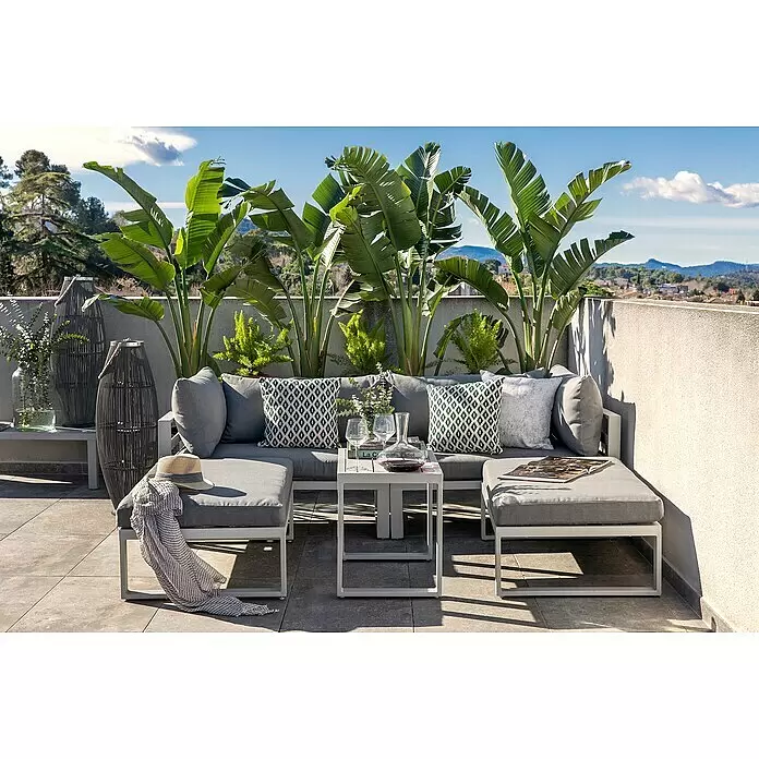 Sunfun Hannah Loungemöbel-Set - 5 -tlg., Aluminium, Grau - Eine graue Outdoor-Lounge-Gruppe mit weißem Rahmen auf einer Sonnenterrasse, umgeben von tropischen Pflanzen.