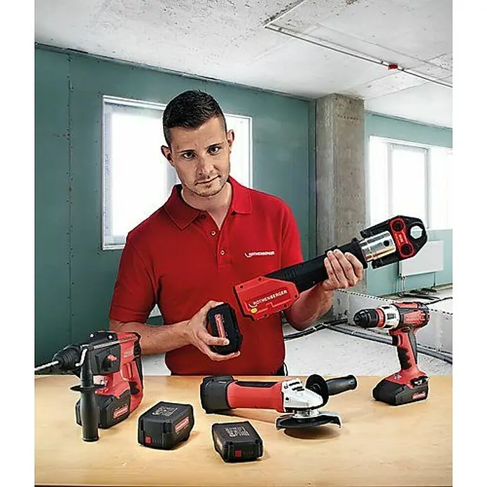 Rothenberger Industrial Batería Romax RO BP - 18 V, 2 Ah, Iones de litio - Herramientas Rothenberger: Un hombre muestra herramientas inalámbricas, incluyendo un taladro, una amoladora angular y una prensa, en una mesa.