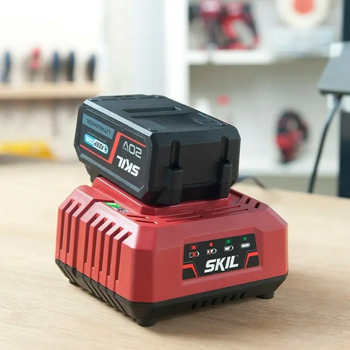 Skil PWRCore 20V Akku-Ladegerät 20V Max - Passend für: Skil Energy Platform Akkus 20V Max - SKIL 20V Akku auf einem roten Ladegerät. Das Ladegerät steht auf einem Tisch und ist bereit, den Akku aufzuladen.