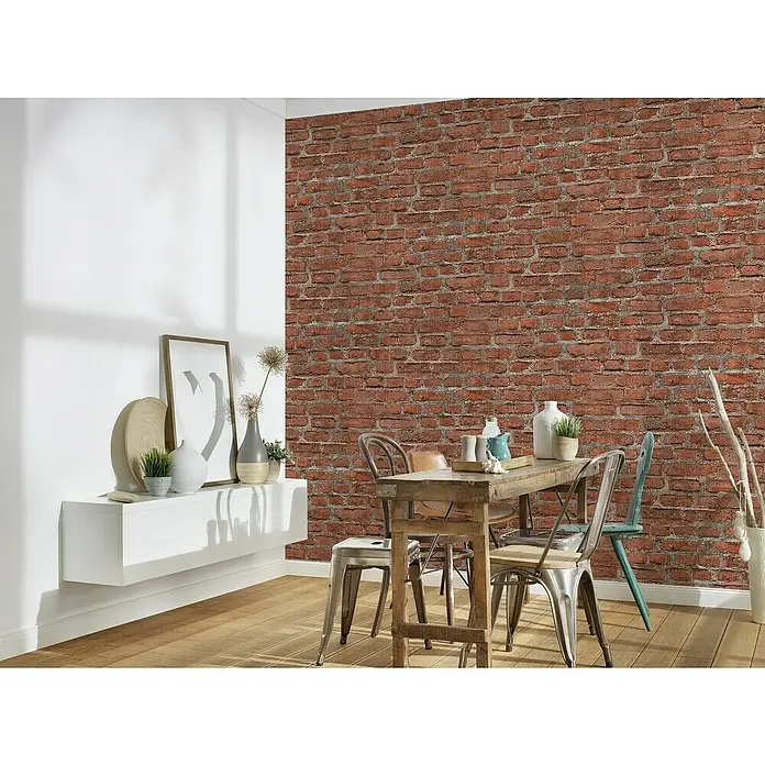 A.S. Création Elements Vliestapete Backsteinmauer - Rot/Grau, Steinoptik, 10,05 x 0,53 m - Essbereich mit Holztisch und Metallstühlen vor einer Ziegelwand, ergänzt durch ein weißes Sideboard mit Dekorationen.
