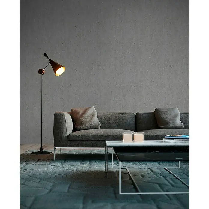 A.S. Création Elements Vliestapete Uni - Grau, Betonoptik, 10,05 x 0,53 m - Elegante Stehlampe beleuchtet stilvolles Wohnzimmer mit Couch, Tisch und Teppich. Moderne Innenarchitektur mit Fokus auf Beleuchtung und Möbeldesign.