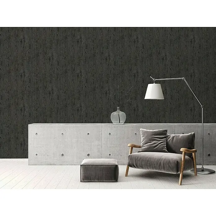 A.S. Création Elements Vliestapete Patina - Schwarz, Metalloptik, 10,05 x 0,53 m - Gemütlicher grauer Samtsessel mit Hocker vor einer stilvollen Betongarderobe und Lampe, die ein modernes und entspannendes Ambiente schafft.