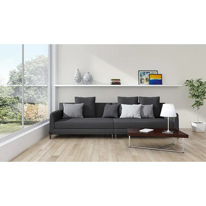A.S. Création New Life Vliestapete mit feiner Struktur - Creme, Uni, 10,05 x 0,53 m - Wohnzimmerblick mit modernem dunkelgrauen Sofa mit Kissen, das eine einladende und stilvolle Atmosphäre schafft.