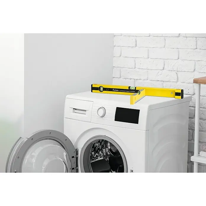 Flüwa Wasserwaage - Länge: 60 cm, Gelb/Schwarz, 16-cm-Lineal - Eine Wasserwaage der Marke FLÜWA liegt auf einer weißen Waschmaschine, um sicherzustellen, dass sie eben steht und korrekt funktioniert.
