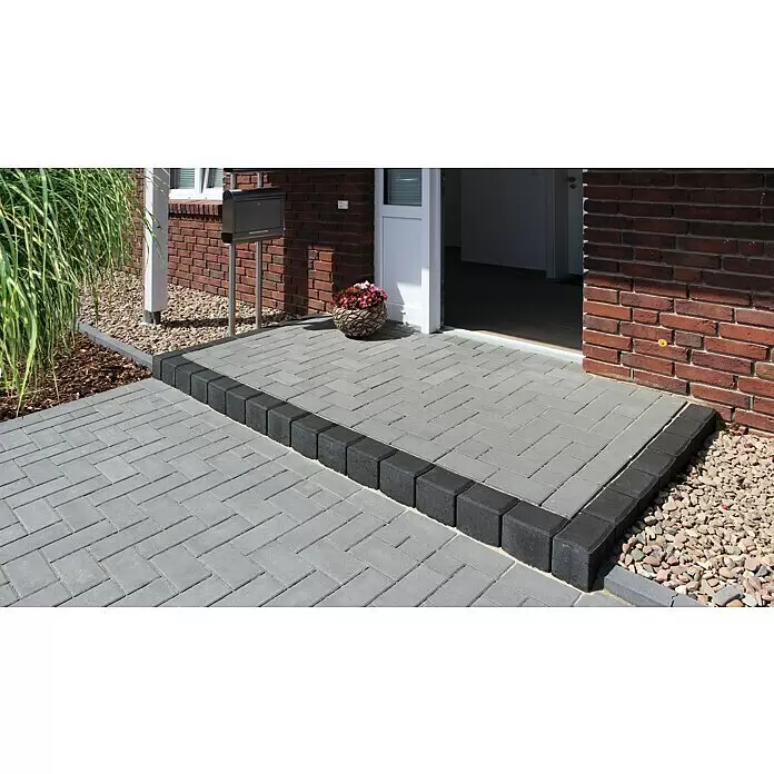 Diephaus Rechteckpalisade - 16,5 x 12 x 40 cm, Anthrazit, Beton - Graue Verbundpflastersteine bilden eine Terrasse und einen Weg mit dunkelgrauer Umrandung zum Hauseingang.