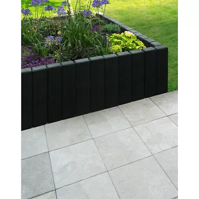 Diephaus Rechteckpalisade - 16,5 x 12 x 150 cm, Anthrazit, Beton - Schwarze Beetumrandung aus Blöcken trennt ein farbenfrohes Hochbeet von einer hellen Terrasse.