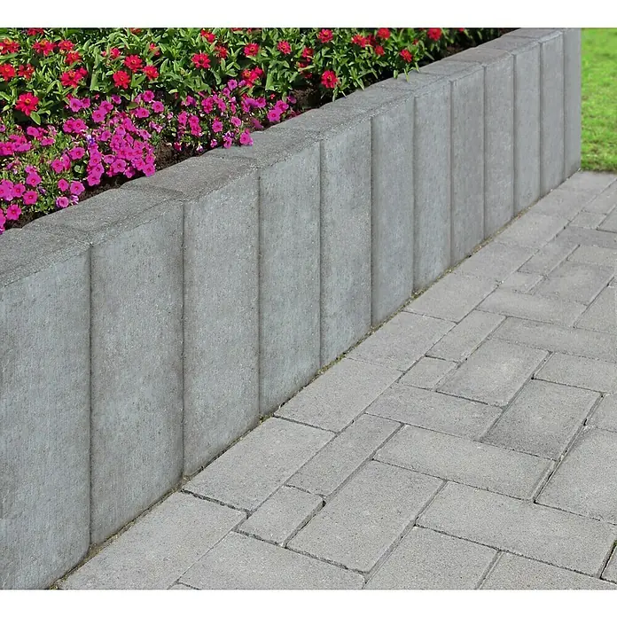 Diephaus Rechteckpalisade - 16,5 x 12 x 100 cm, Grau, Beton - Nahaufnahme einer grauen Steinmauer, die ein Blumenbeet mit roten und pinkfarbenen Blumen begrenzt, neben einem gepflasterten Weg.