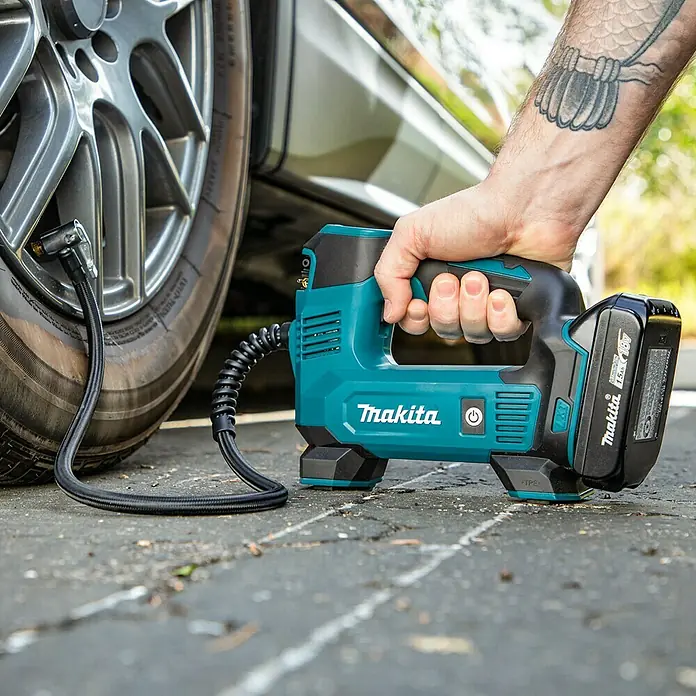 Makita LXT 18V Compresor de batería DMP180Z - 18 V, Sin batería, 8,3 bar - Primer plano de un inflador inalámbrico Makita inflando un neumático de coche, centrado en la herramienta y su aplicación.