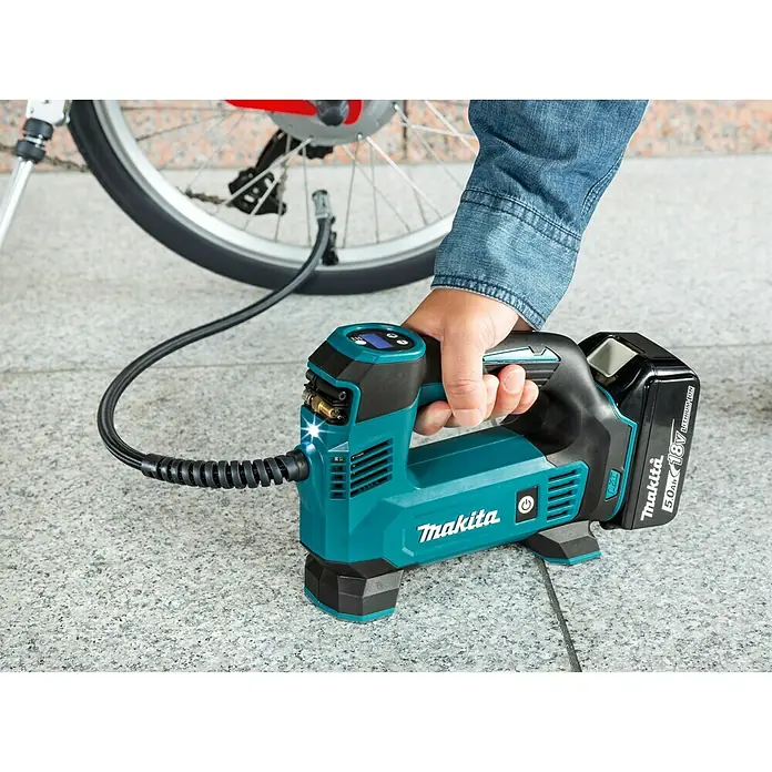 Makita LXT 18V Akku-Kompressor DMP180Z - 18 V, Ohne Akku, 8,3 bar - Akkuluftpumpe von Makita in Gebrauch, ein Fahrradreifen wird aufgepumpt. Das Gerät ist blaugrün und schwarz und hat einen Akku.