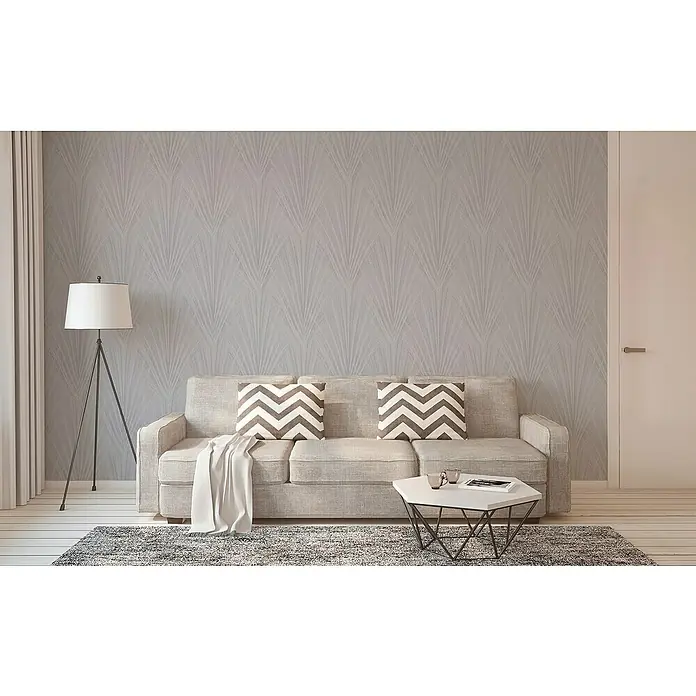 A.S. Création New Elegance Vliestapete Farn - Grau, Floral, 10,05 x 0,53 m - Elegantes Wohnzimmer mit grauem Sofa, gemusterten Kissen und stilvoller Stehlampe vor einer dekorativen Wand.