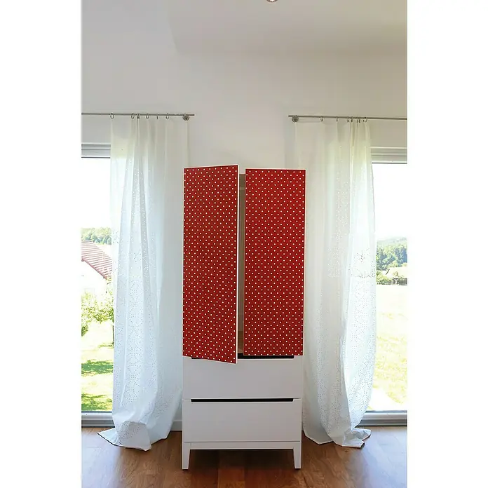D-c-fix Pünktchenfolie Petersen - 200 x 45 cm, Rot, Selbstklebend - Dekorativer Kleiderschrank mit roten Türen und weißen Punkten, platziert vor einem hellen Fenster.