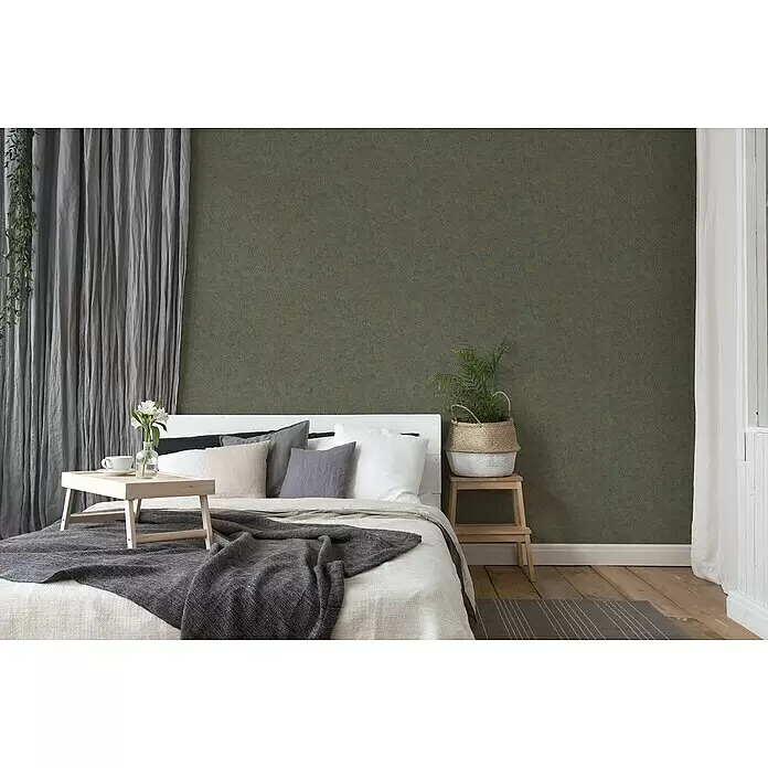 A.S. Création History of Arts Vliestapete - Braun/Blau, Uni, 10,05 x 0,53 m - Ein Schlafzimmer mit Bett, grauen Textilien und einer dunklen, strukturierten grünen Wand schafft eine gemütliche Atmosphäre.