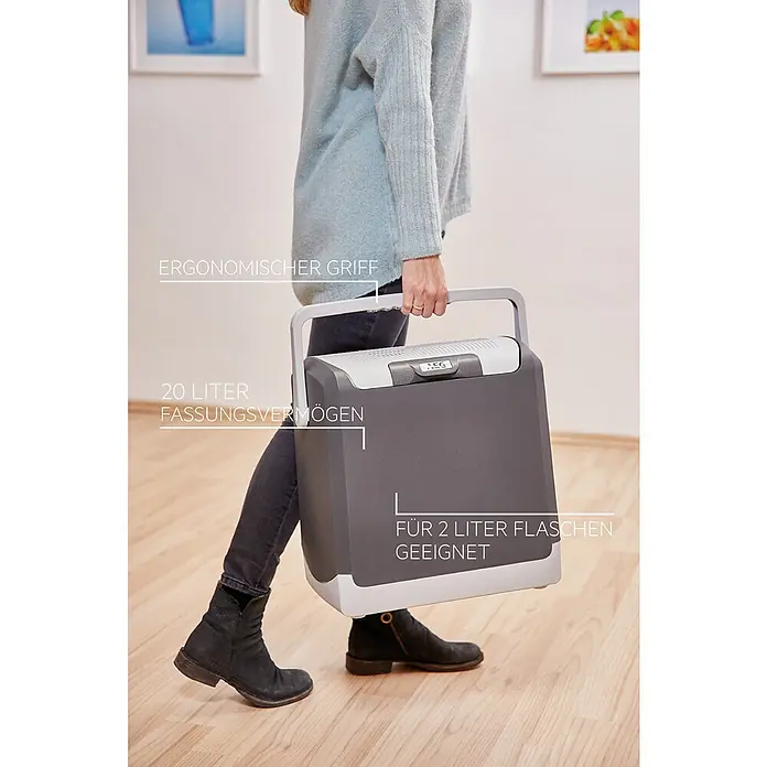 AEG Kühlbox KK20 - Fassungsvermögen: 20 l, Grau - Frau trägt eine tragbare AEG Kühlbox mit ergonomischem Griff, 20 Liter Fassungsvermögen, geeignet für 2 Liter Flaschen.