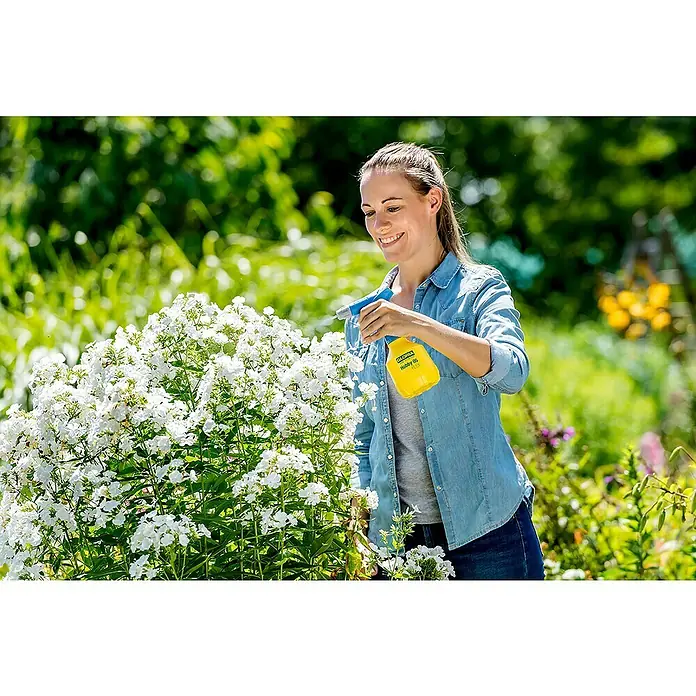 Gloria Handsprüher Hobby 05 FLEX mit Doppelhub - 360 ° Funktion, 0,5 l - Eine Frau gießt Blumen mit einer gelben Gloria Hobby 05 FLEX Sprühflasche im Garten, umgeben von üppigem Grün und bunten Blumen.