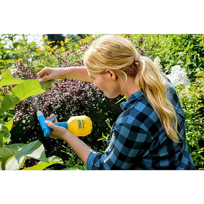 Gloria Handsprüher Hobby 05 FLEX mit Doppelhub - 360 ° Funktion, 0,5 l - Frau, die eine GLORIA Hobby 05 FLEX Sprühflasche benutzt, um eine Pflanze in einem Garten zu besprühen.