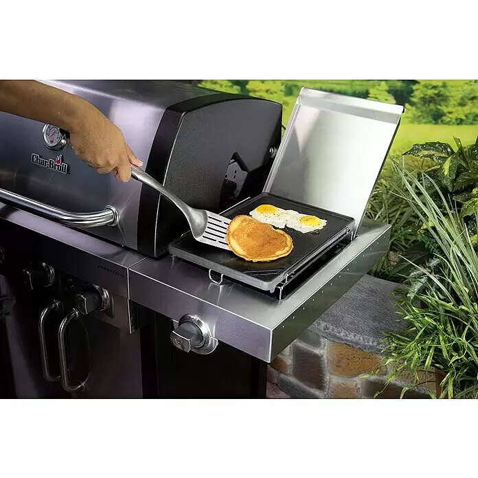 Char-Broil Grillplatte - L x B: 37 x 25,4 cm - Eine Hand wendet einen Pfannkuchen auf einer schwarzen Grillplatte am Edelstahl-Char-Broil-Grill. Daneben braten Eier.