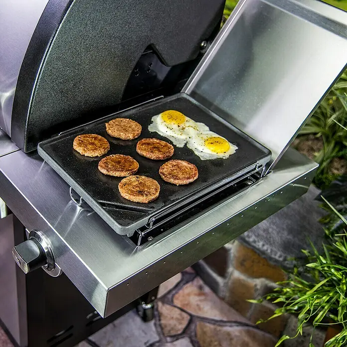 Char-Broil Grillplatte - L x B: 37 x 25,4 cm - Auf einem Grill werden Würstchen und Eier zubereitet. Der Grill ist aus Edelstahl und hat eine schwarze Grillplatte. Leckeres Frühstück im Freien!