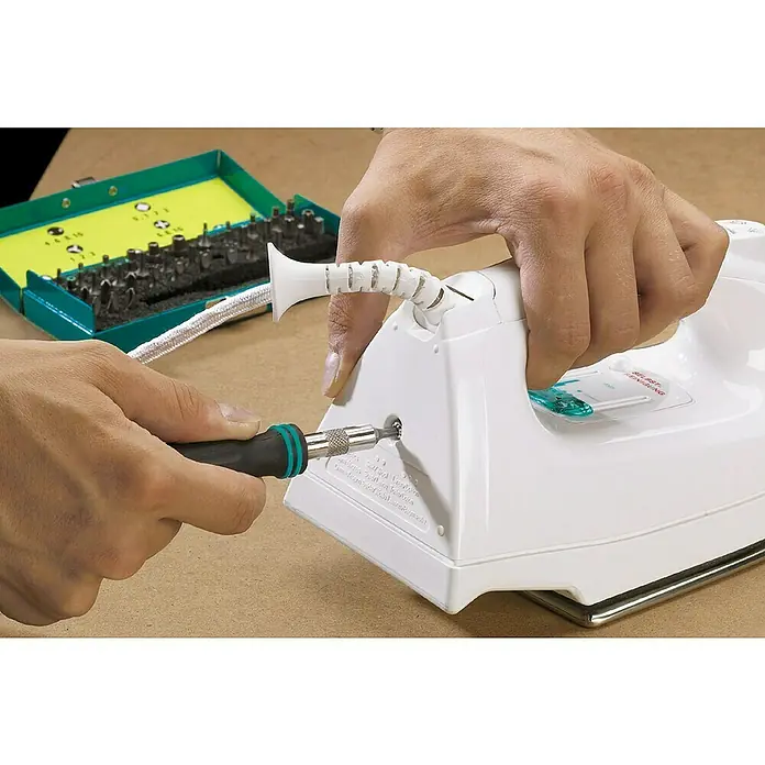 Wolfcraft Bit-Set Safety-Bit-Box - 31 -tlg. - Die Abbildung zeigt ein Bügeleisen, das mit einem Schraubenzieher repariert wird. Das Werkzeugset liegt bereit.