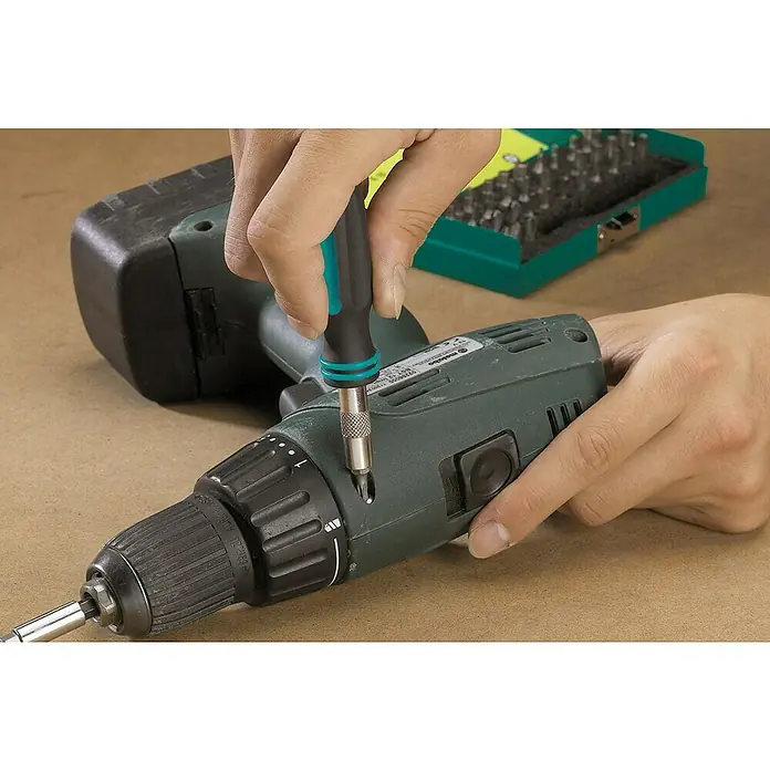 Wolfcraft Bit-Set Safety-Bit-Box - 31 -tlg. - Ein Akkuschrauber wird mit einem Schraubendreher repariert, Werkzeugkasten mit Bits im Hintergrund.