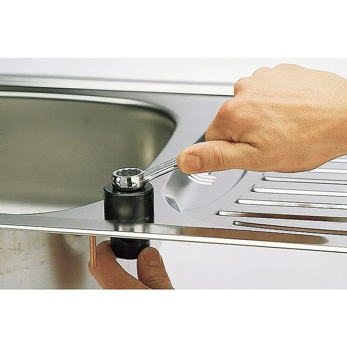 Wolfcraft Lochstanze - 32 mm - Eine Hand benutzt einen Schraubenschlüssel, um die Spüle zu befestigen. Ein unentbehrliches Werkzeug für Sanitärarbeiten, um eine feste und dichte Installation zu gewährleisten.