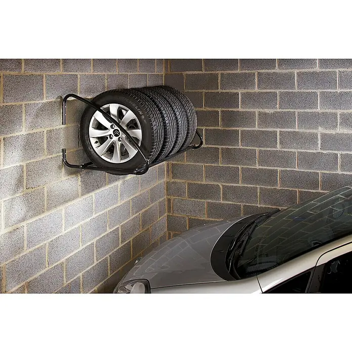 Mottez Metall-Reifen- & Lagerregal - L x B x H: 100 x 75 x 60 cm, Traglast: 100 kg - Eine Reifenaufbewahrungshalterung an der Wand, die vier Reifen und eine silberne Autofelge in einer Garage hält.