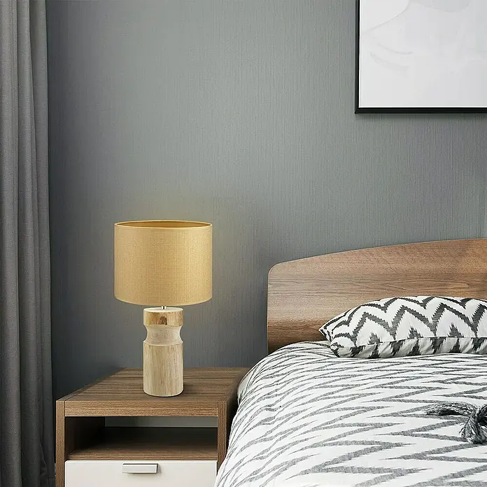 Home Sweet Home Lampenfuß Bodo - 40 W, Farbe: Braun, Höhe: 30 cm - Nahaufnahme einer Nachttischlampe mit einem Holzsockel und einem beigen Lampenschirm auf einem Nachttisch neben einem Bett.