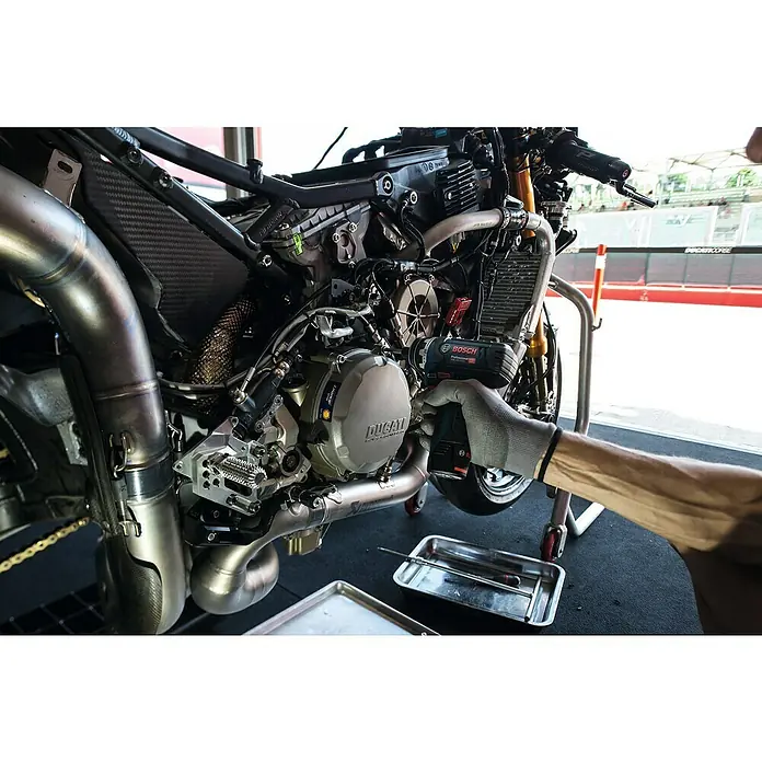 Bosch Professional Akku-Bohrschrauber GSR 12V-15 FC - 12 V, 2 Akkus, 2 Ah, 30 Nm, 11 -tlg. - Detailaufnahme eines Ducati-Motorrads, an dem mit einem Bosch-Akkuschrauber gearbeitet wird, Fokus auf Präzision und Technologie.