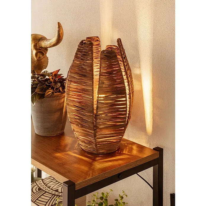 Baufan Pronatur Wandfarbe Lehmfarbe - Naturweiß, Matt, 10 l, Lösemittelfrei - Dekorative Tischleuchte aus Rattan auf einem Regal, die warmes Licht ausstrahlt und eine gemütliche Atmosphäre schafft.
