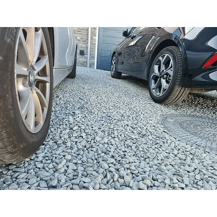 ACO Self Stabilisierungsmatte Kieswabe Eco - Polypropylen, 80 x 60 cm - Nahaufnahme von zwei Autos auf einem Kiesweg, der die Textur und das Material der Reifen und des Untergrunds hervorhebt.
