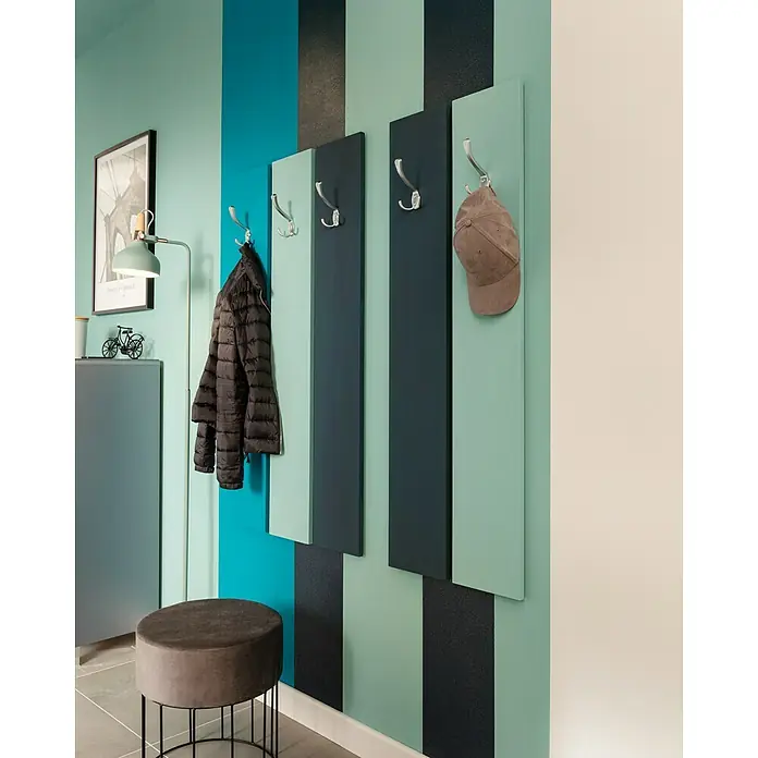 SCHÖNER WOHNEN-Farbe Wandfarbe Trendfarbe - Lagune, Matt, 2,5 l, Konservierungsmittelfrei - Eine stilvolle Garderobe mit farbigen Paneelen und silbernen Haken, an denen Jacke und Mütze hängen. Ein moderner Flur mit Sitzhocker.