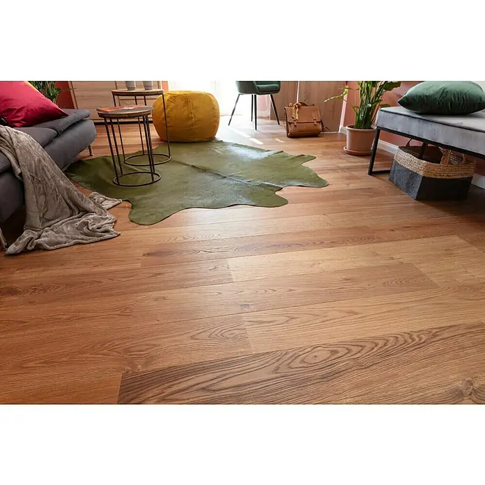 Living by Haro Designbodenmuster Eiche Mokkabraun - 290 x 173 x 12 mm, Landhausdiele - Einladendes Wohnzimmer mit einem grauen Sofa, einem grünen Teppich und einem stilvollen Holzboden, der Wärme und Eleganz ausstrahlt.