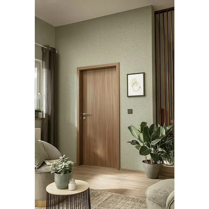 SCHÖNER WOHNEN-Kollektion Vliestapete Unistruktur - Olivgrün, Uni, 10,05 x 0,53 m - Einladender Raum mit einer modernen Holztür, die Wärme und Stil ausstrahlt, ergänzt durch sanfte Farben und grüne Pflanzen für eine harmonische Atmosphäre.