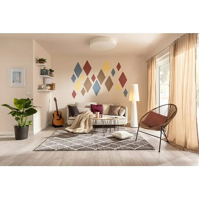 SCHÖNER WOHNEN-Farbe Wandfarbe Designfarbe - Leichtes Leinenbeige, Matt, 2,5 l, Konservierungsmittelfrei - Wohnzimmer mit Teppich, Sofa, Sessel und dekorativen Elementen. Das Wohnzimmer ist hell und freundlich eingerichtet und lädt zum Verweilen ein.