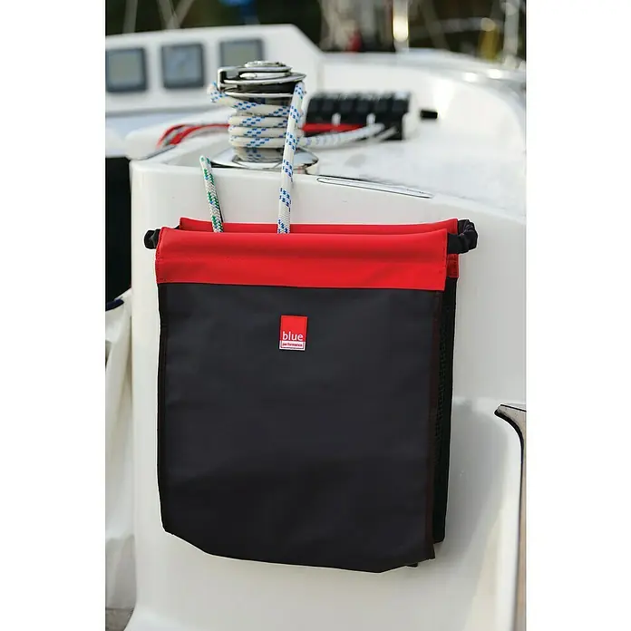 Blue Performance Cockpit-Tasche - L x B x H: 350 x 300 x 120 mm, Schwarz/Rot - Diese Aufnahme zeigt eine schwarze Blue Performance Segeltasche mit roten Akzenten, befestigt an einem weißen Segelboot, mit Seilen, die durch die Oberseite laufen.