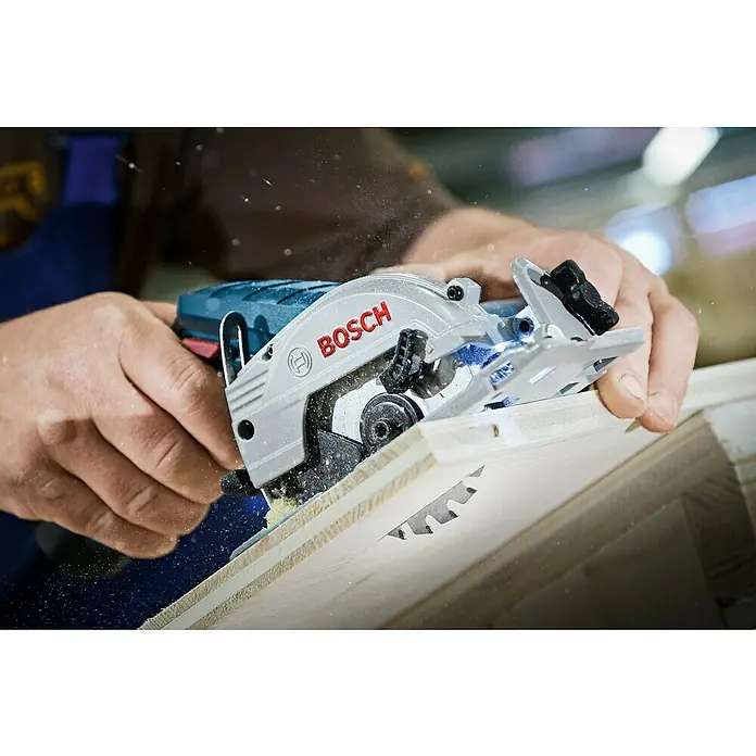 Bosch Professional Sierra circular de batería GKS 12V-26 L-Boxx - 12 V, 2 baterías, 3 Ah, Número de revoluciones de marcha en vacío: 1.400 r.p.m. - Detalle de una mini sierra circular Bosch cortando madera, ideal para cortes precisos en proyectos de taller.